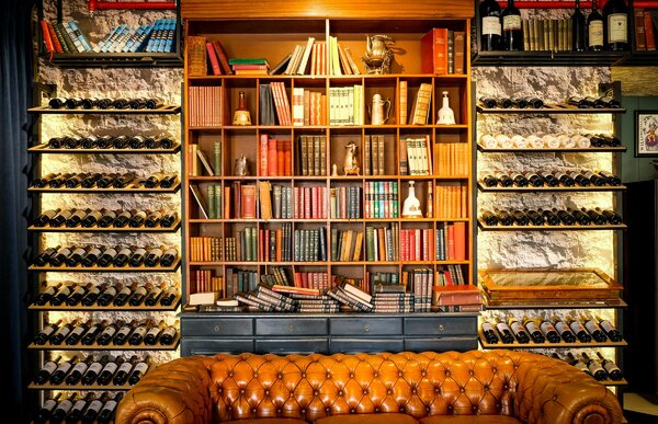 Cantinetta vino integrata in soggiorno con libreria e divano in pelle
