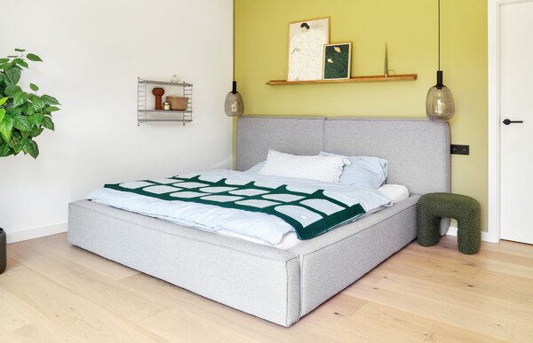 Camera da letto con testiera imbottita e parete gialla