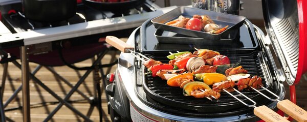 Barbecue elettrico con spiedini di carne e verdure sul terrazzo
