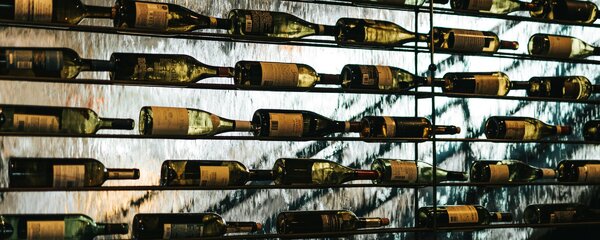 Cantinetta vino in casa con bottiglie su rastrelliera metallica retroilluminata