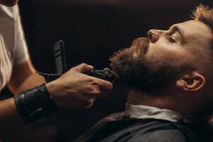 Fotografia Young bearded man getting beard haircut, zamrznutitonovi