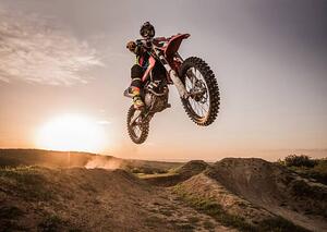 Fotografia Motocross rider performing high jump at sunset, skynesher