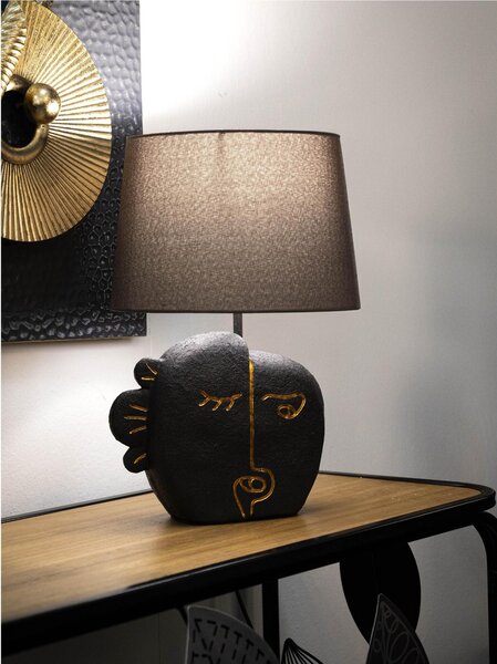 Lampada da tavolo in resina dalla forma ispirata ad un volto tribale Dimensioni 27,5xh 39,5 cm in resina e paralume in tessuto grigio